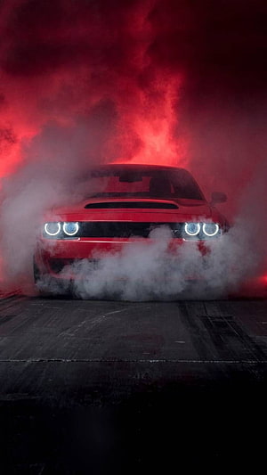 Red Dodge Challenger SRT emerging from thick smoke under dramatic red lighting HD phone wallpaper