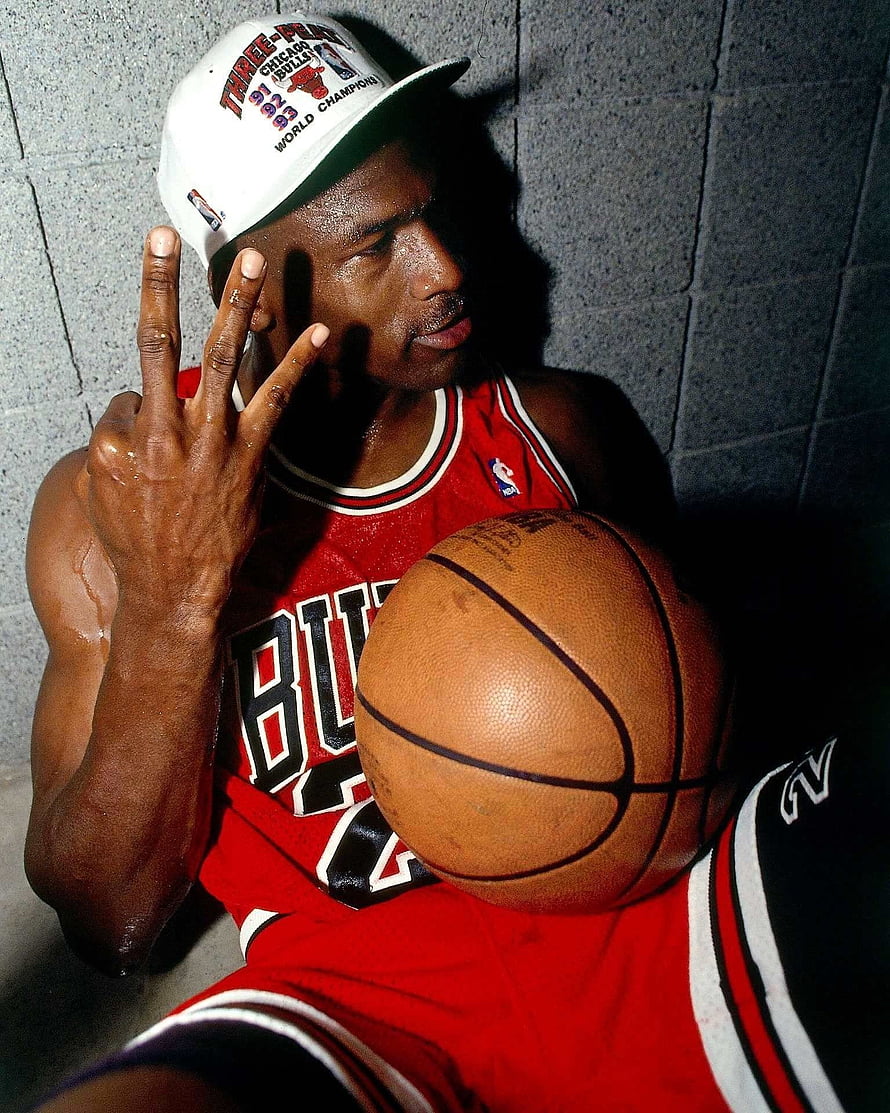 Michael Jordan in Chicago Bulls jersey holding basketball with championship cap HD phone wallpaper