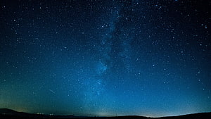 Milky Way Galaxy Arching Over a Dark Horizon Under a Deep Blue Starry Night Sky HD wallpaper