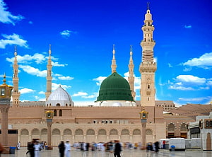 The Prophet's Mosque in Medina with the iconic Green Dome and towering minarets under a bright blue sky HD wallpaper