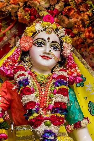 Beautifully adorned Radha statue with vibrant floral garlands and traditional jewelry HD phone wallpaper