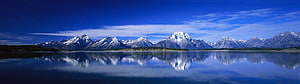 Snow-Capped Mountain Range Reflected in a Calm Alpine Lake Under a Deep Blue Sky HD wallpaper
