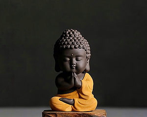 Cute Baby Buddha Statue in Yellow Robe Sitting in Meditation Pose HD wallpaper