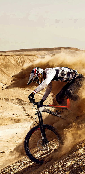 Mountain Biker Carving Through Dusty Desert Trail on a Canyon Bike HD phone wallpaper