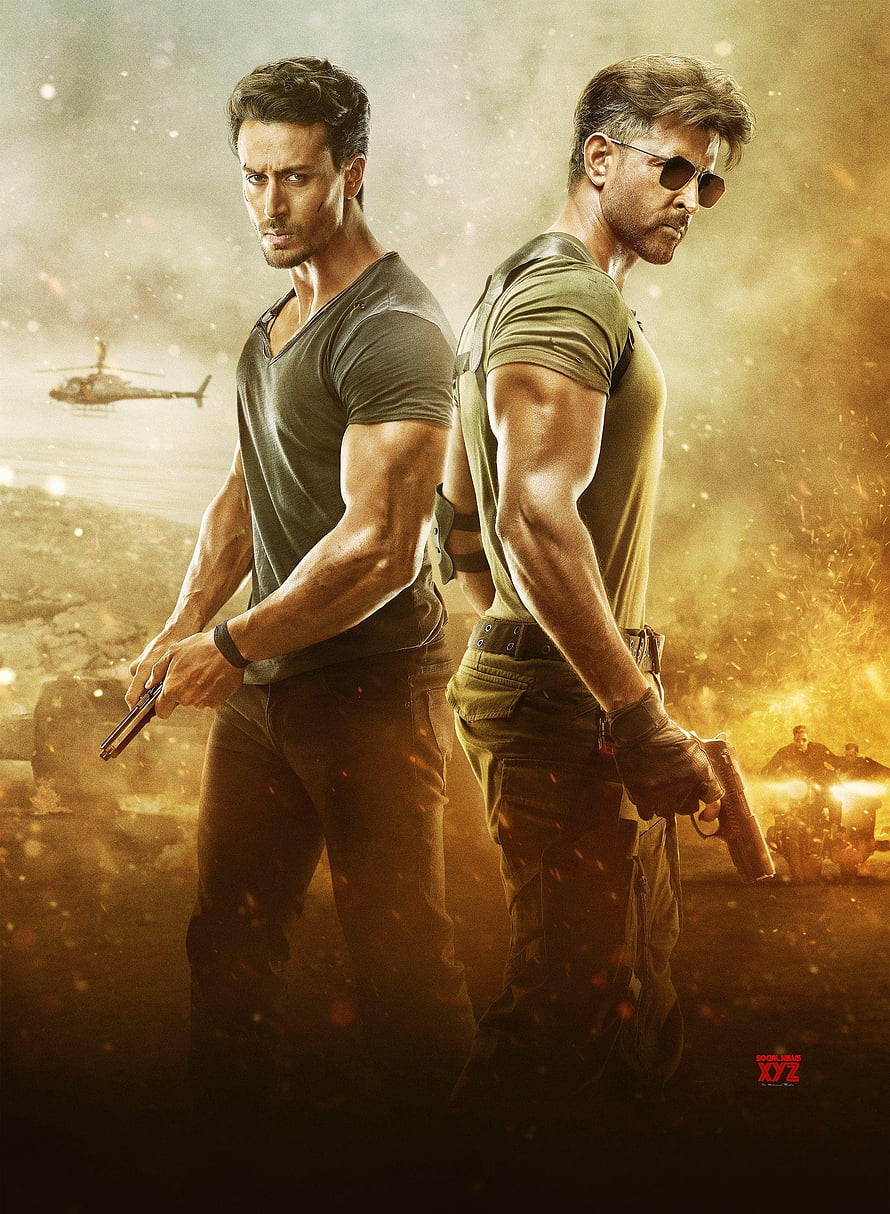 Action movie poster featuring two muscular men standing back to back with guns in a war zone HD phone wallpaper