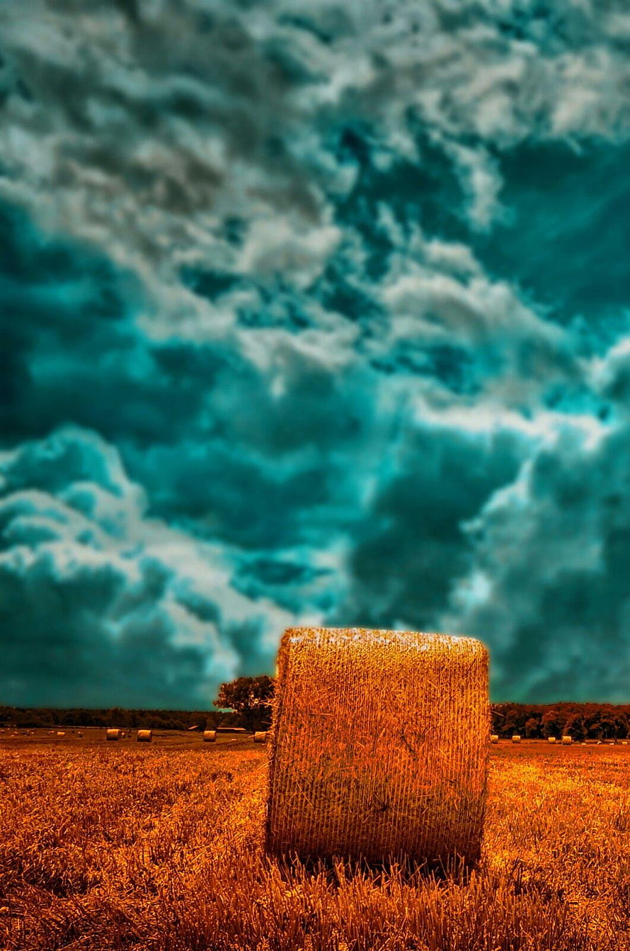 Dramatic Hay Bale in Golden Field Under Stormy Teal Sky HD phone wallpaper