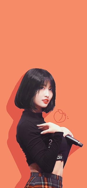 Momo from TWICE in a black turtleneck and plaid skirt holding a microphone against an orange background HD phone wallpaper