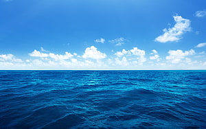 Calm Ocean Horizon Under a Bright Blue Sky with Scattered Clouds HD wallpaper