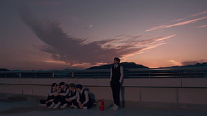 TXT Members Silhouetted Against a Dramatic Sunset Sky on a Rooftop Terrace HD wallpaper