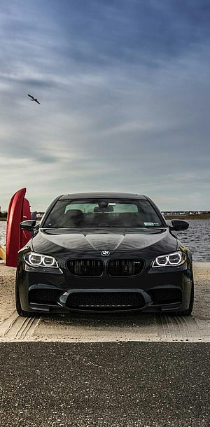 Black BMW M5 F10 Front View Parked on Lakeside Concrete with Red Kayak HD phone wallpaper