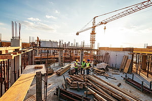 Construction workers on a building site with tower crane and rebar at golden hour HD wallpaper