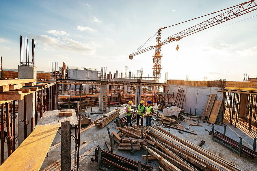 Construction workers on a building site with tower crane and rebar at golden hour HD wallpaper