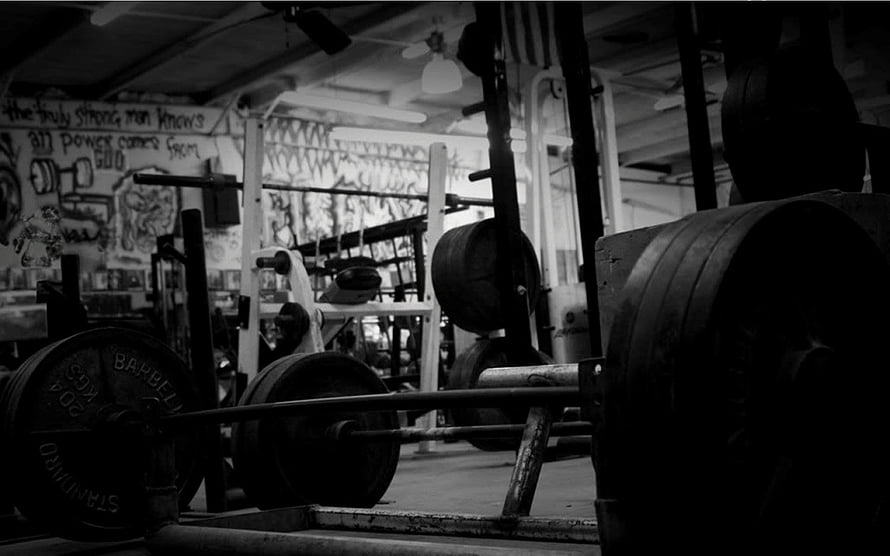 Moody Black and White Gym Interior Featuring Barbell Plates and Weightlifting Equipment HD wallpaper