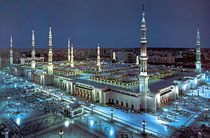 Al-Masjid an-Nabawi in Medina at Night with Illuminated Minarets and Crowds HD wallpaper