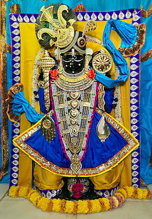 Ornate Black Idol of Lord Krishna Adorned with Gold Jewelry and Blue Silk Garments HD phone wallpaper