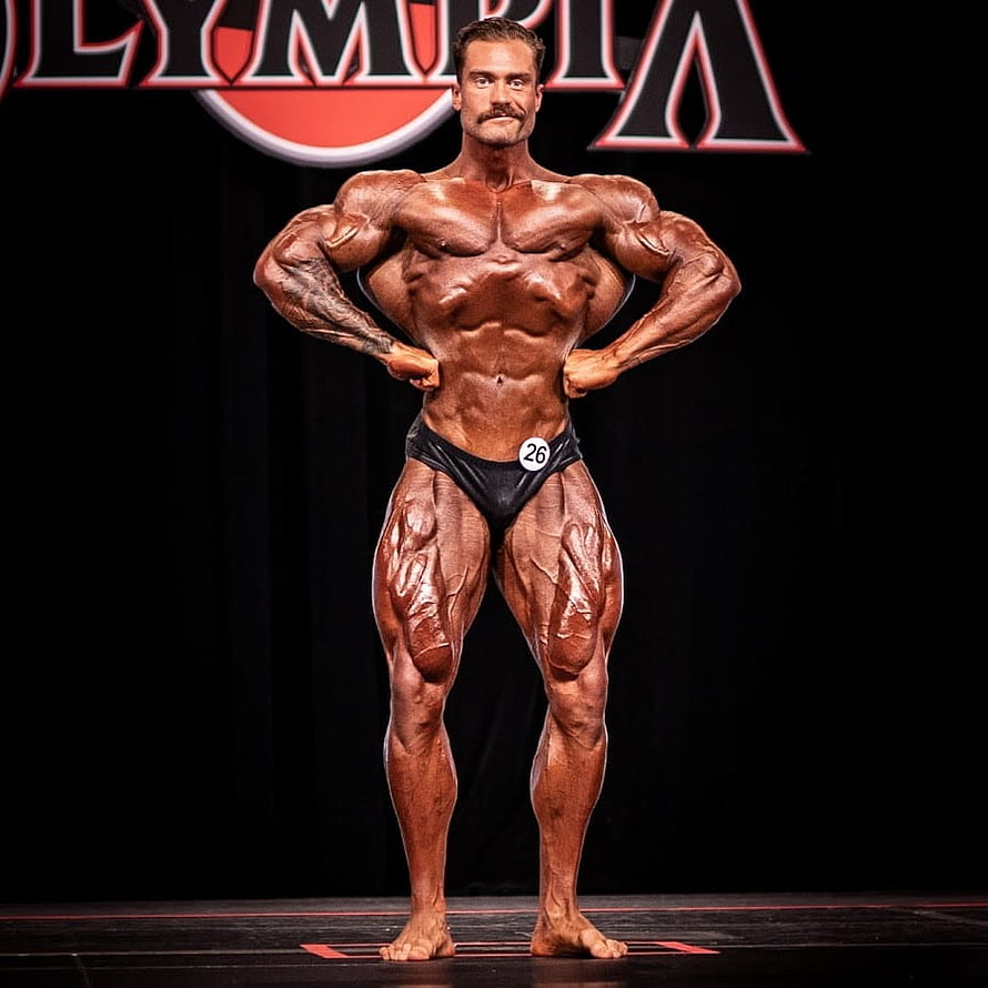 Chris Bumstead posing on stage at Mr. Olympia bodybuilding competition HD phone wallpaper