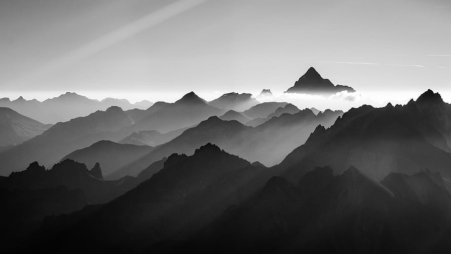 Monochromatic mountain range silhouettes layered in atmospheric mist and fog HD wallpaper
