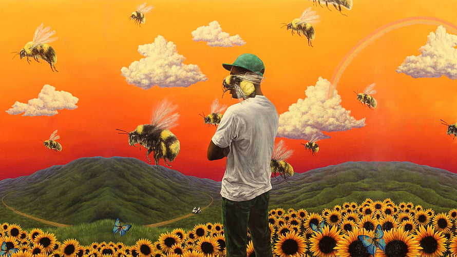Tyler the Creator in a surreal sunflower field with giant bees and a vibrant orange sky HD wallpaper