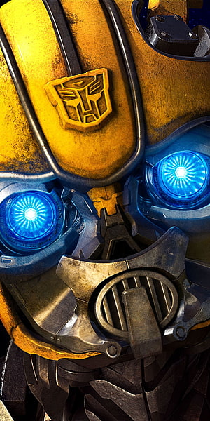Bumblebee Close-Up Face with Glowing Blue Eyes and Autobot Emblem HD phone wallpaper