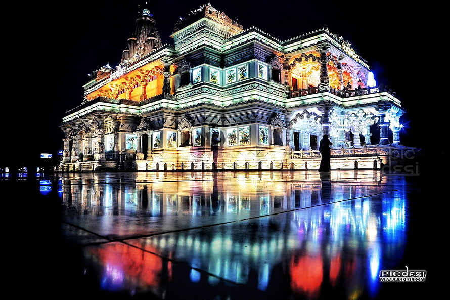 Prem Mandir Vrindavan illuminated at night with colorful reflections on wet pavement HD wallpaper