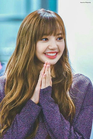 Lisa from Blackpink smiling warmly with hands pressed together in a purple sweater HD phone wallpaper