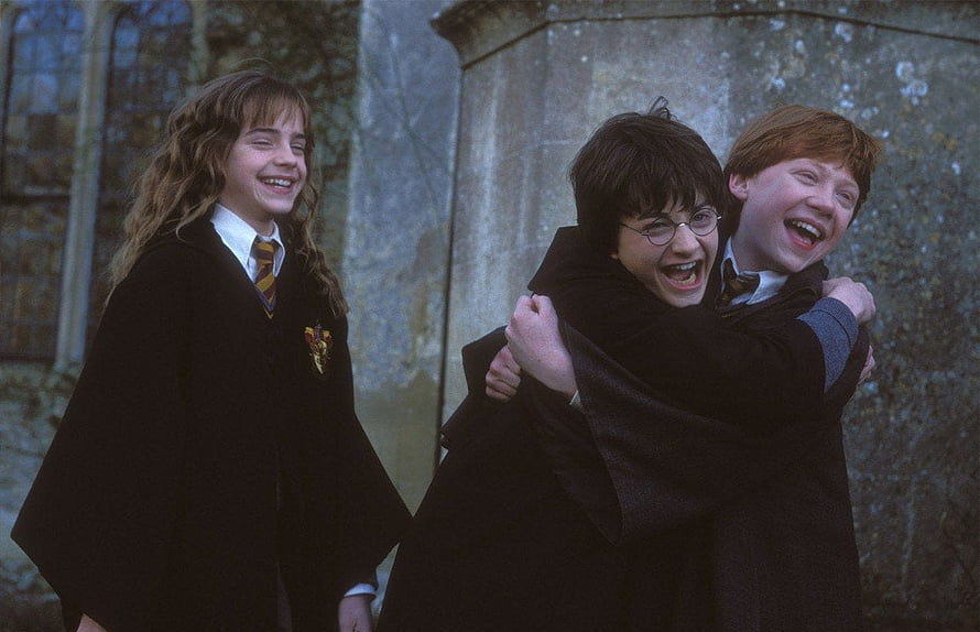 Harry Potter, Ron Weasley, and Hermione Granger laughing together in Hogwarts robes HD wallpaper