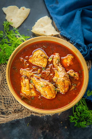 Rich Tomato Chicken Curry with Flatbread and Fresh Herbs on a Rustic Table HD phone wallpaper