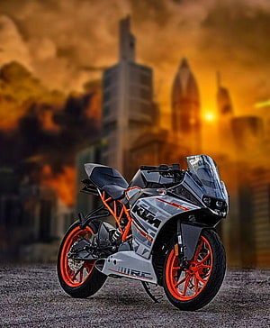 KTM RC 390 sport motorcycle with orange frame parked against a dramatic sunset city skyline HD phone wallpaper