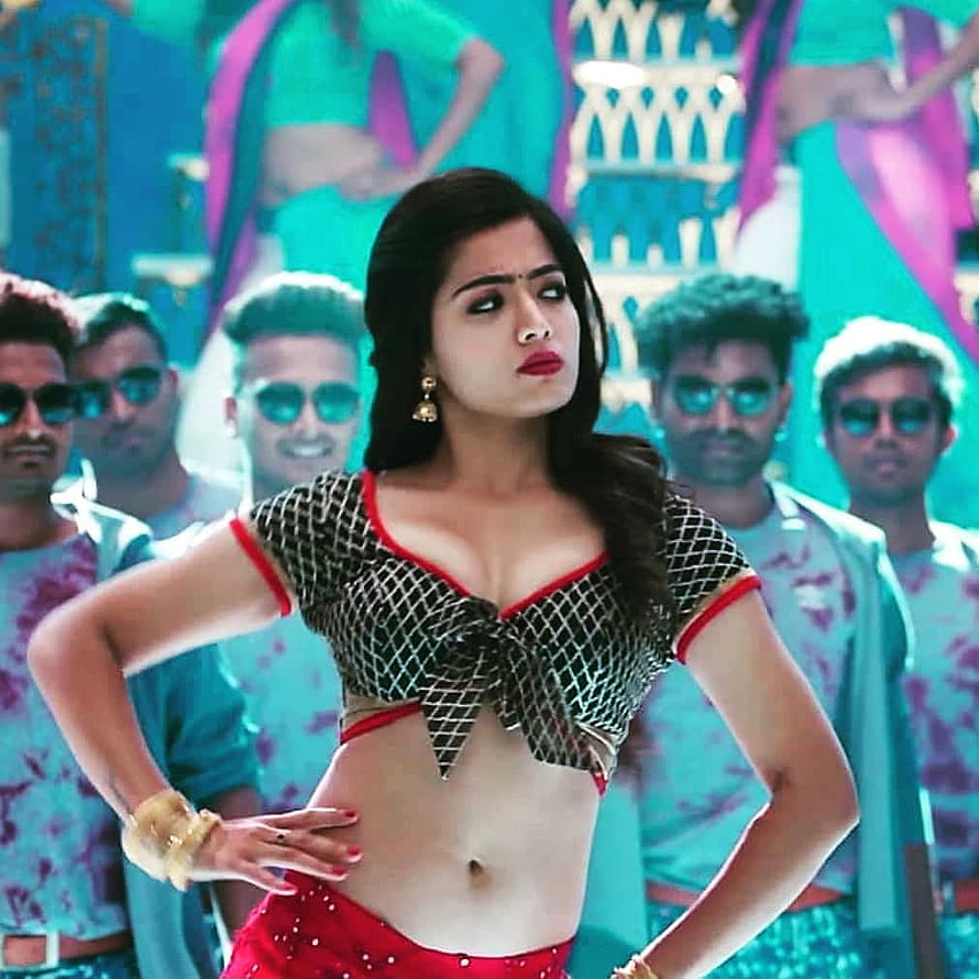 Rashmika Mandana in a bold red and black dance costume with backup dancers in a vibrant teal set HD phone wallpaper