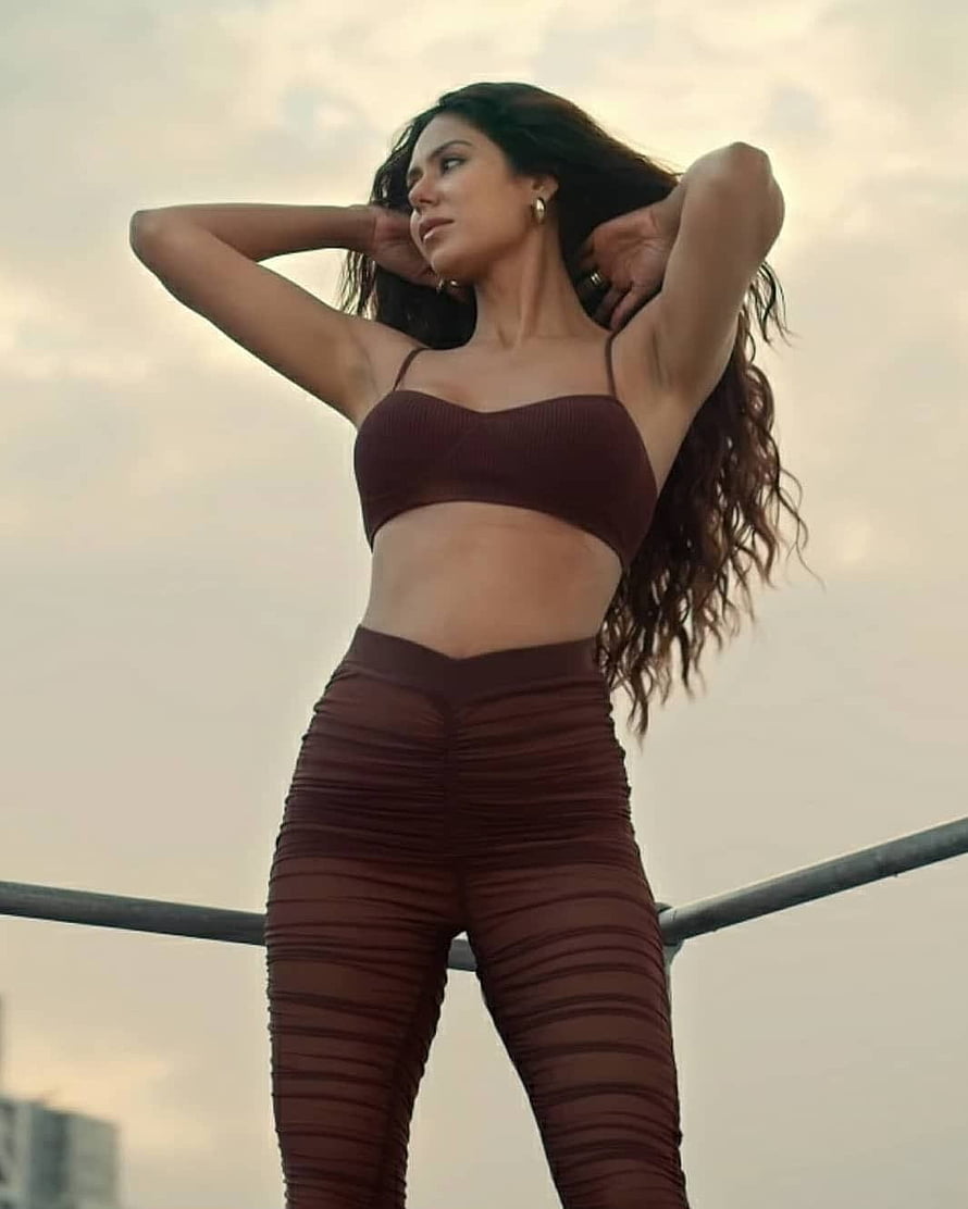 Sonam Bajwa in a maroon ribbed two-piece outfit posing on a rooftop at dusk HD phone wallpaper