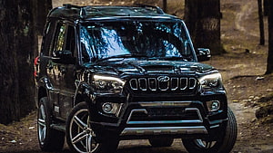 Black Mahindra Thar SUV parked on a dirt road in a forest with headlights on HD wallpaper