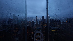 Moody Cityscape View Through Rain-Streaked Window at Dusk HD wallpaper