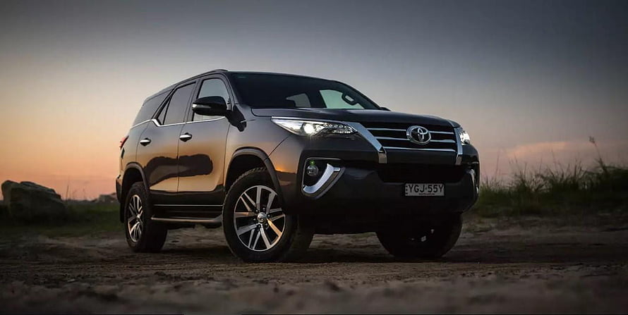 Black Toyota Fortuner SUV parked on a dirt road at sunset with dramatic sky HD wallpaper