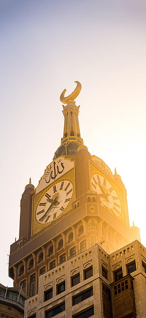Makkah Royal Clock Tower at sunset with golden crescent spire and intricate Islamic architecture HD phone wallpaper
