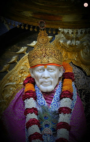 Sacred Statue of Sai Baba Adorned with Golden Crown and Flower Garlands HD phone wallpaper
