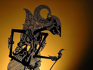 Intricate Wayang Kulit Shadow Puppet Silhouette Against Warm Golden Backdrop HD wallpaper