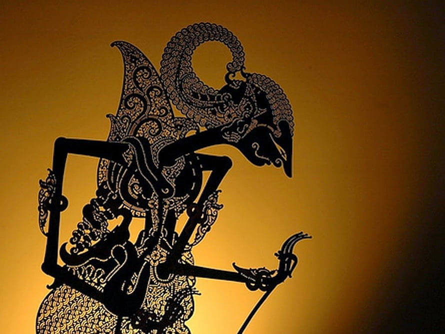 Intricate Wayang Kulit Shadow Puppet Silhouette Against Warm Golden Backdrop HD wallpaper