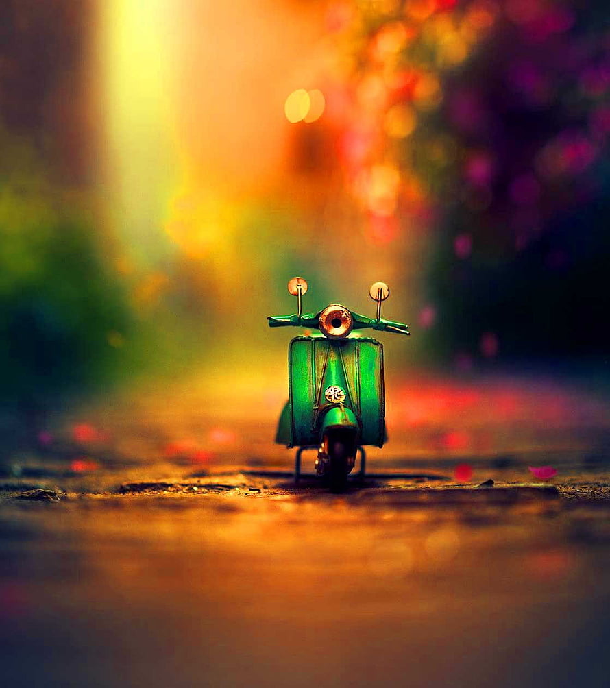 Green Vespa Scooter on a Sunlit Path with Warm Bokeh Background HD phone wallpaper