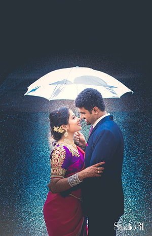 South Indian couple in traditional attire sharing a tender moment under a white umbrella in the rain HD phone wallpaper