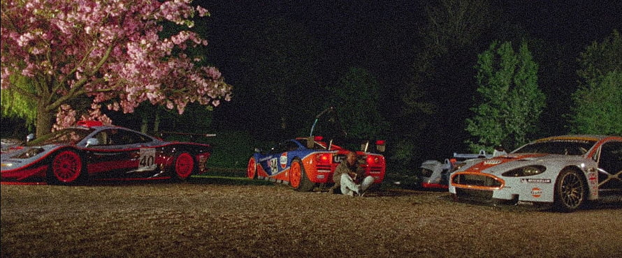 Nighttime scene with three racing cars parked on gravel beneath a blooming cherry blossom tree HD wallpaper
