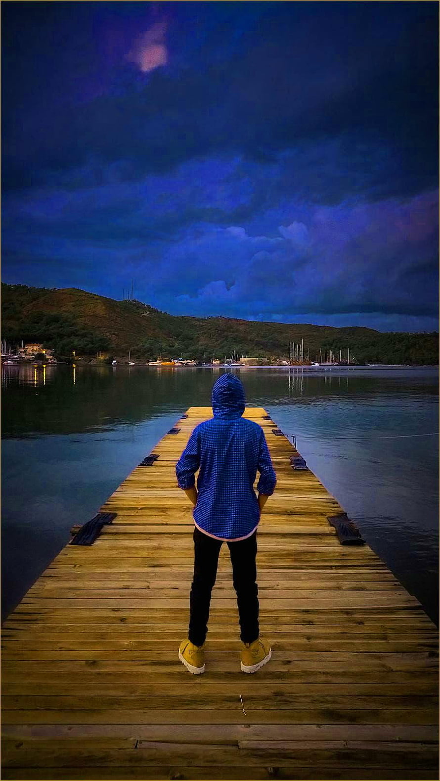 Person in Blue Hoodie Standing on Wooden Pier at Dusk HD phone wallpaper