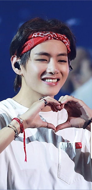 V from BTS smiling and making a heart gesture with a red bandana on stage HD phone wallpaper