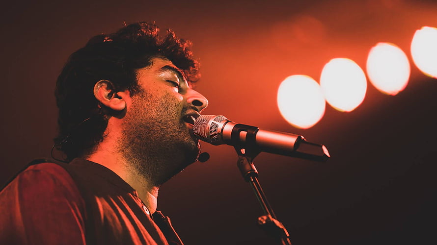 Arijit Singh performing live on stage with dramatic red lighting and microphone HD wallpaper