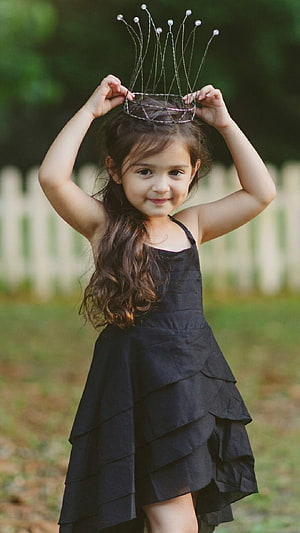 Cute Little Girl Wearing a Black Dress and Holding a Wire Crown Outdoors HD phone wallpaper