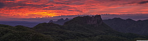 Dramatic Red Sunset Over Rugged Mountain Peaks and Forested Hills HD wallpaper