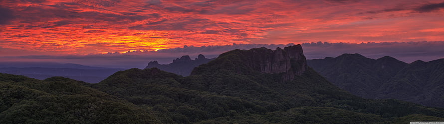 Dramatic Red Sunset Over Rugged Mountain Peaks and Forested Hills HD wallpaper