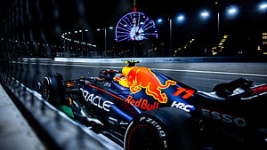 Red Bull Racing Formula 1 car on track at night with illuminated Ferris wheel in background HD wallpaper