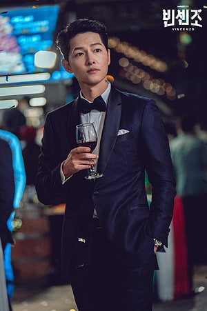 Song Joong Ki as Vincenzo Cassano in a tuxedo holding a glass of red wine at a formal event HD phone wallpaper