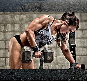 Female Athlete Performing Dumbbell Row in Industrial Gym Setting HD wallpaper
