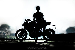 Silhouette of a Biker Sitting on a Motorcycle Against a Bright Hazy Background HD wallpaper